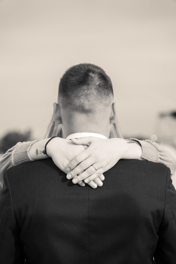 Black and white photo of a couple hugging, with a wider shot capturing more of the moment.