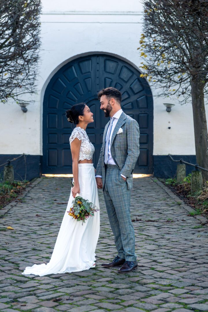 Newlywed couple looking at each other at Brundlund Castle entrance.