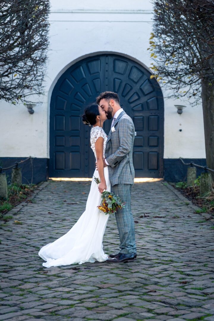Newlywed couple sharing a kiss in front of the castle entrance.