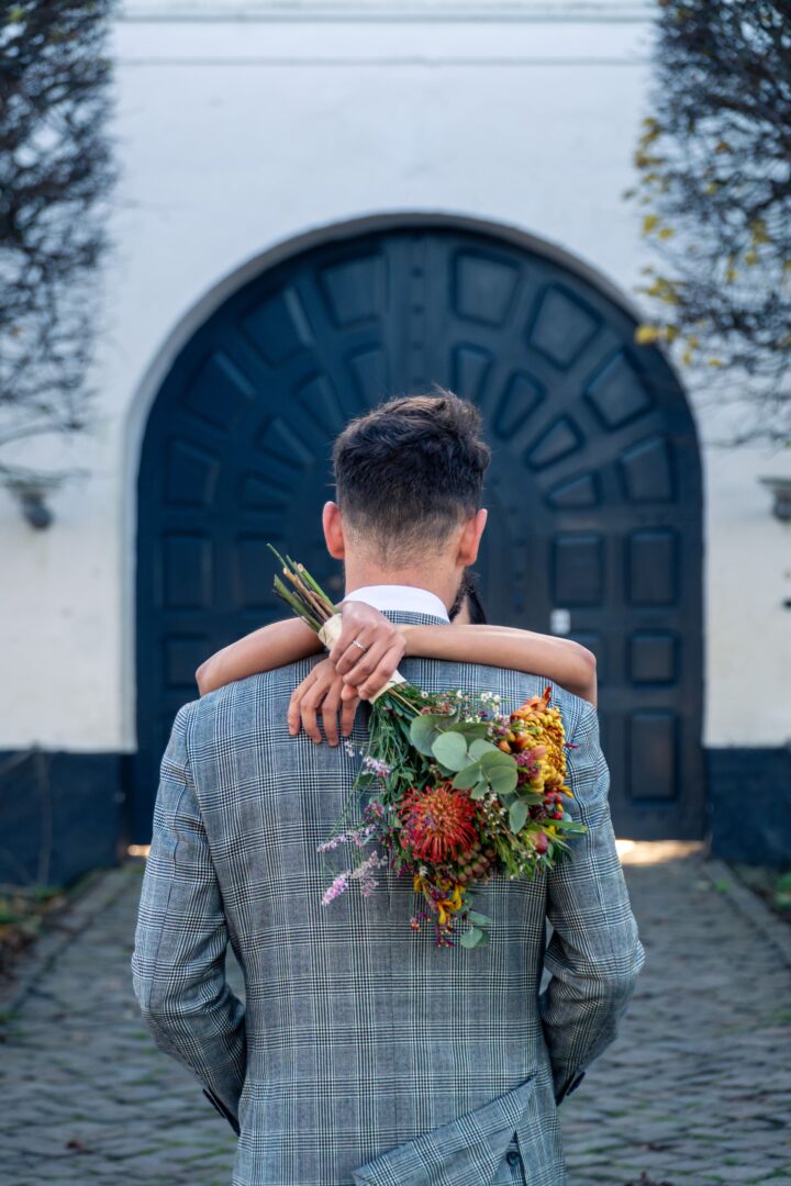 Bride hugging the groom with his back towards the camera at the castle entrance.