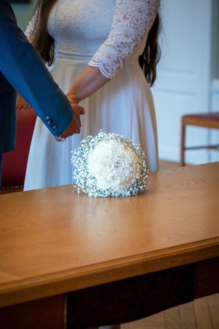 Bouquet of flowers on the table as the couple holds hands in the town hall.