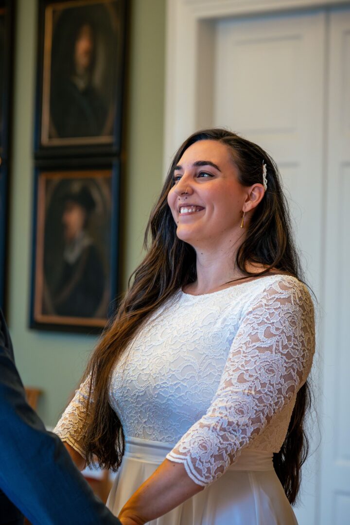 Bride smiling at the groom in the town hall, holding hands and sharing a joyful moment.