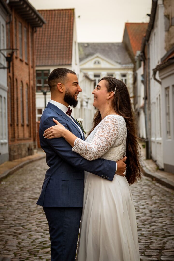 Newlywed couple standing in a beautiful street in Aabenraa, gazing deeply into each other's eyes.