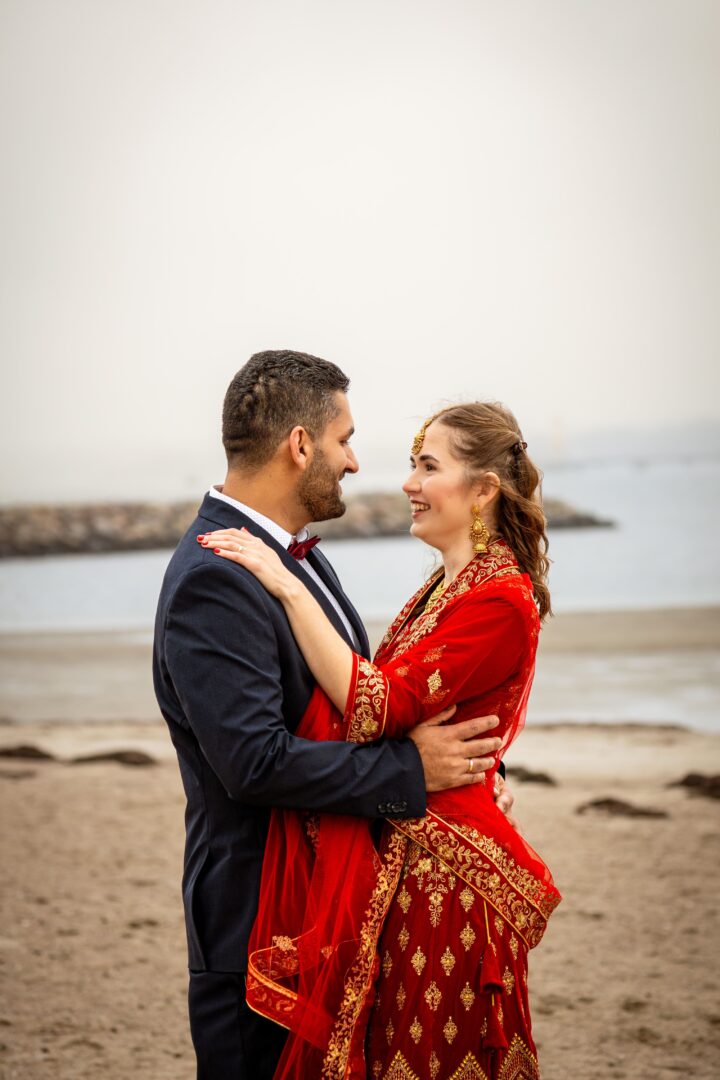 Newlywed couple sharing a tender moment with eye contact, standing close together on the beach after their wedding in Denmark.