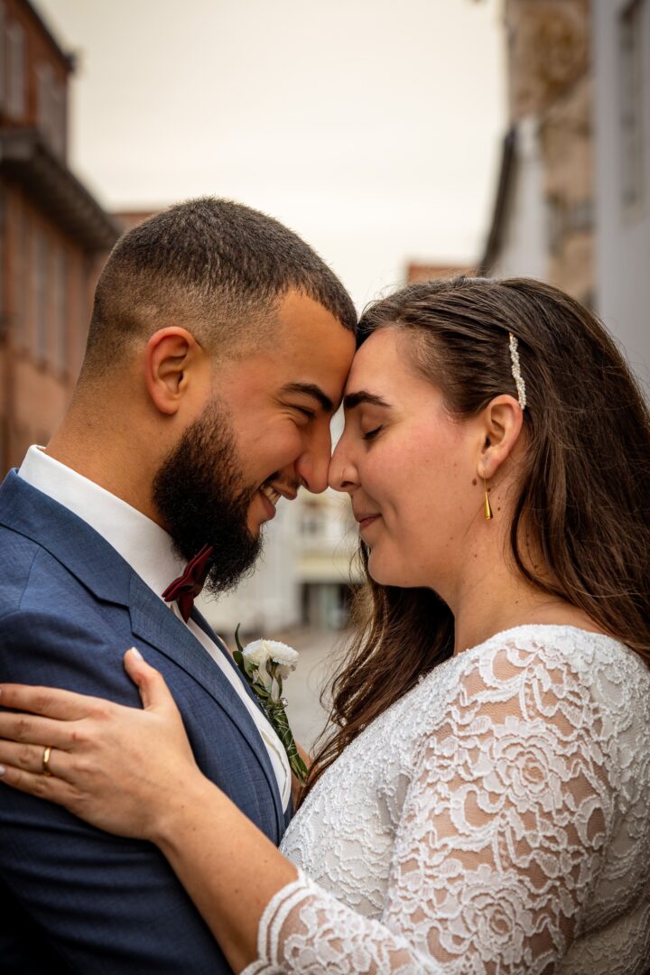 Close-up portrait of the couple in a charming old street, touching noses affectionately.
