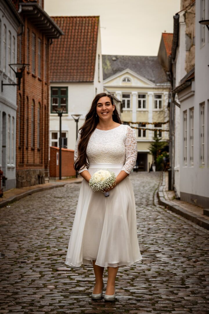 Full-body portrait of the bride standing in a beautiful historic setting, smiling with joy.