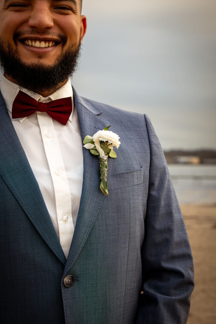 Close-up of the groom’s flower pinned to his suit, with the beach setting softly blurred in the background.