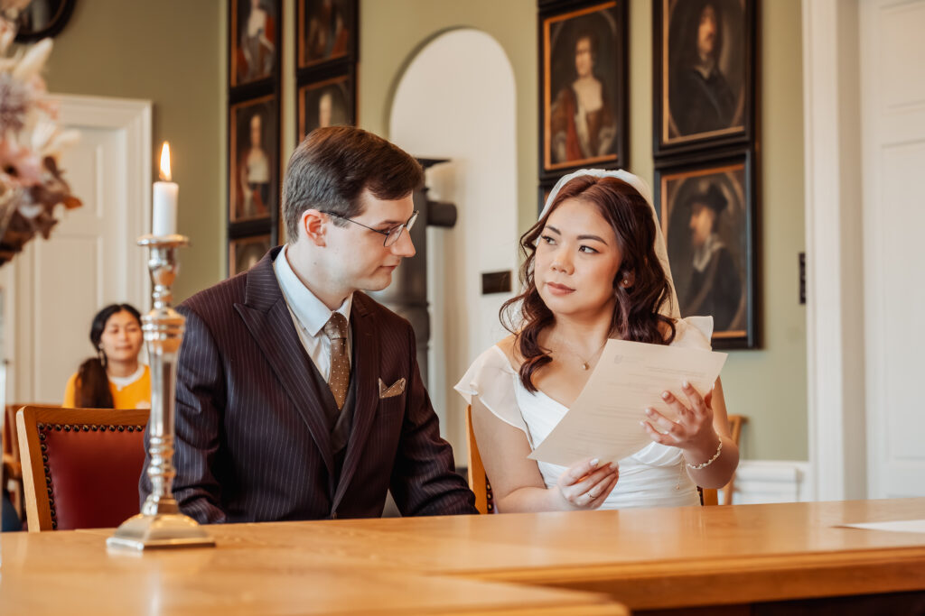 The couple signing their marriage documents at Aabenraa Town Hall while the registrar looks on.