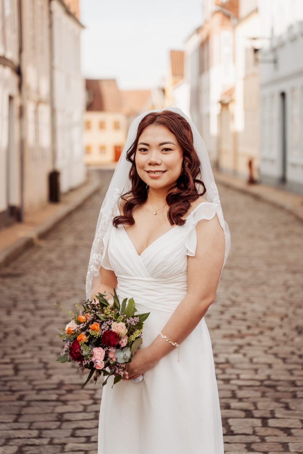Bride holding her bouquet in a cobbled street in Aabenraa after the town hall ceremony.