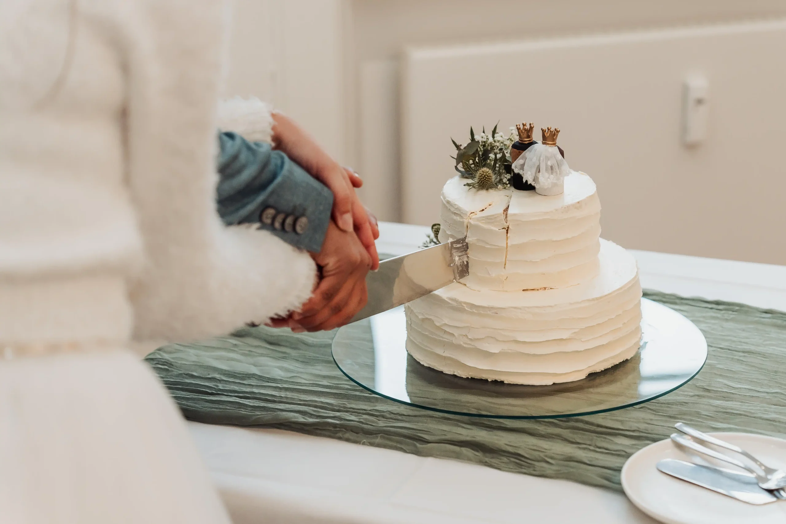 The couple cuts their wedding cake together, sharing a sweet and memorable moment, symbolizing their union and celebration of love.