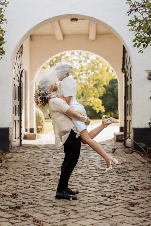 groom lifting the bride under the archway after their wedding