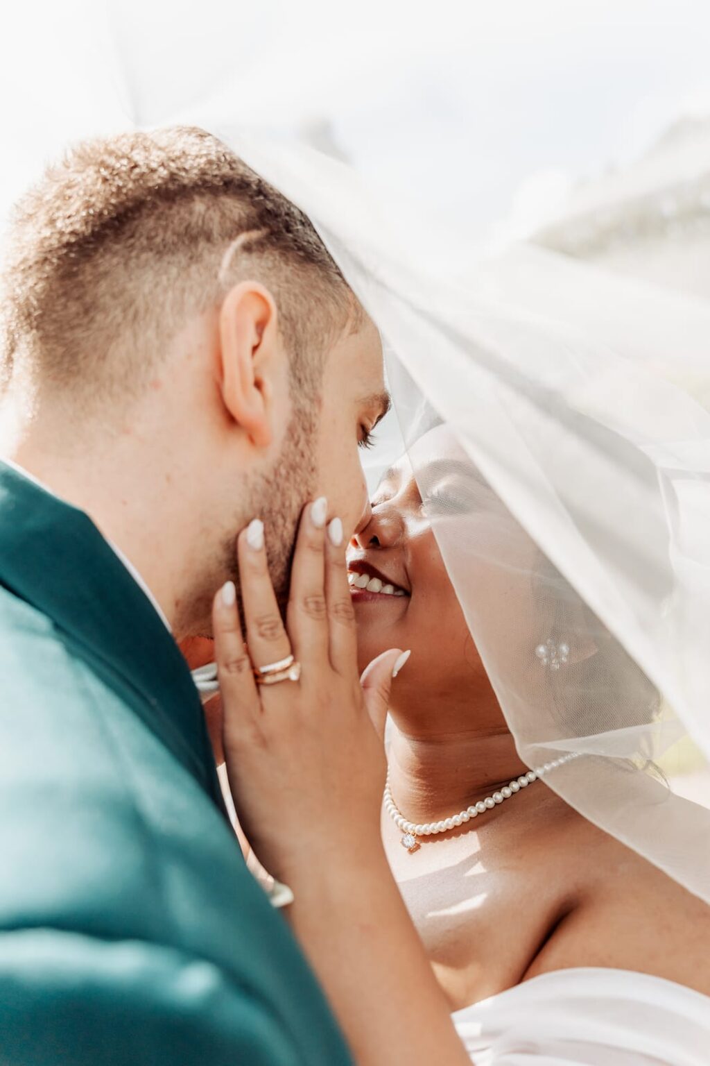 Bride resting her hand on his cheek beneath her veil at Schackenborg Castle, both smiling