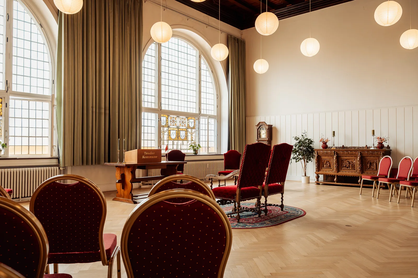 The ceremony room at Jomfrustien 8 in Tønder, with tall arched windows and two red velvet chairs