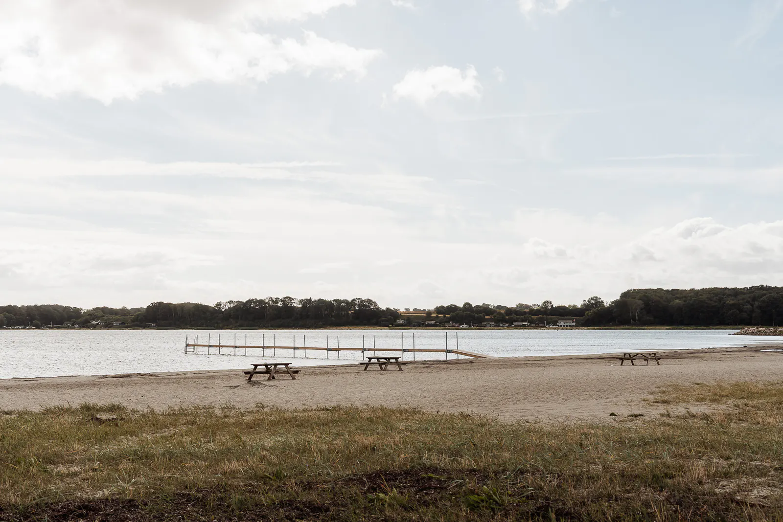 A wooden jetty and picnic tables on the beach at Hejlsminde Strand