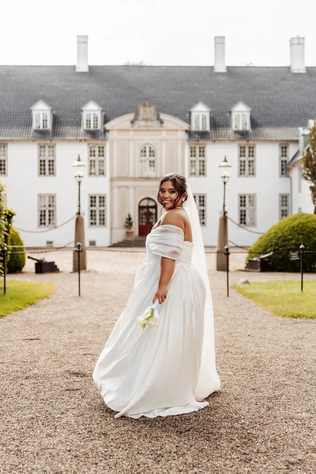 Bride turning to smile over her shoulder at Schackenborg Castle near Tønder