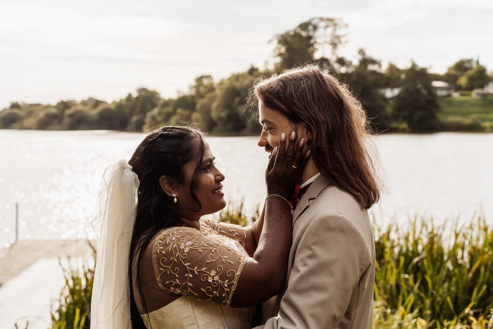 Bride holds the face of her groom by the lake in Nordborg